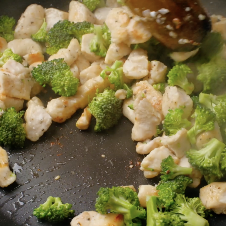 Broccoli florets being cooked along with chicken cubes.