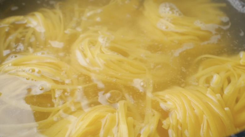 Fettuccini pasta being boiled in a hot of water.