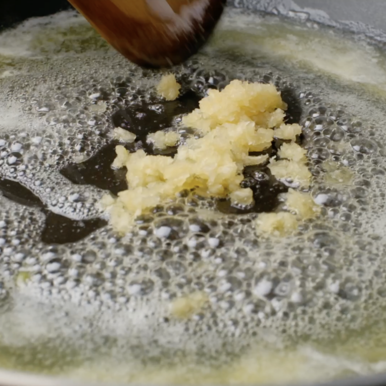 Garlic being sautéed in butter in a pot.