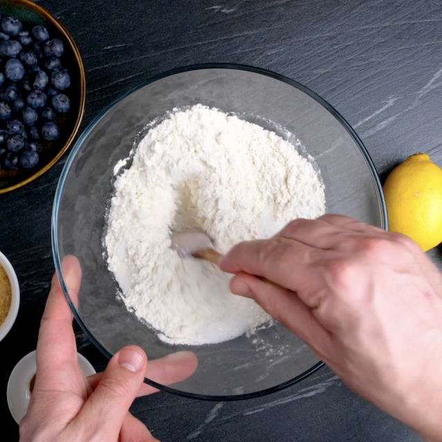 Flour, sugar, salt, and baking powder being mixed in a large bowl.