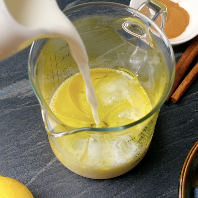 Milk being poured into a measuring cup with oil and egg mixture.
