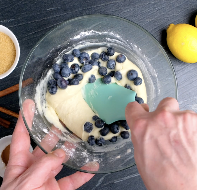Fresh blueberries being folded into muffin batter.
