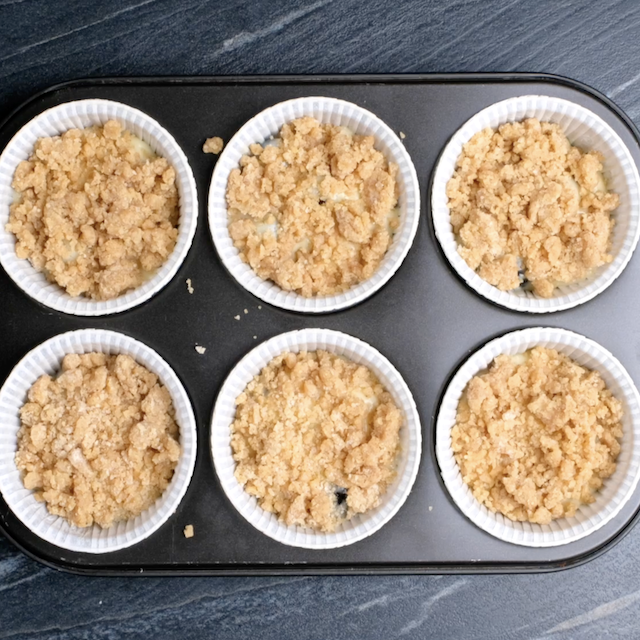 Streusel topping on top of batter in muffin tins.