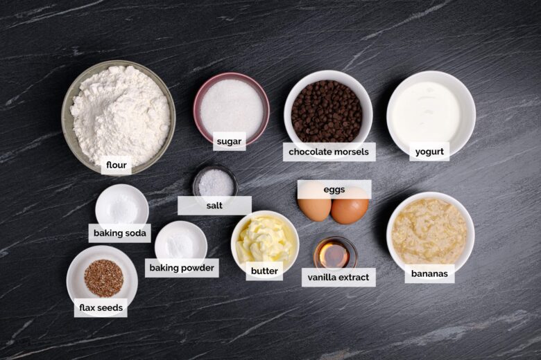 Overhead shot of ingredients to make moist chocolate chip banana bread on a dark surface.