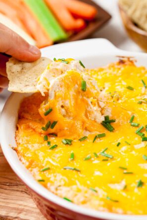 A tortilla chip is dipped into a baked Frank's buffalo chicken dip.