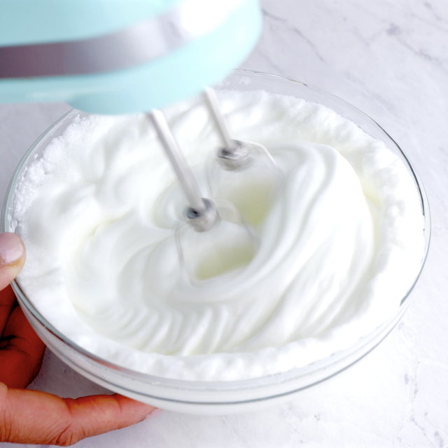 Egg whites being whisked using a hand mixer.