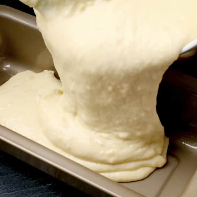 Lemon olive oil cake batter being poured into a loaf pan.