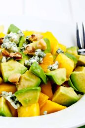 Closeup shot of mango avocado salad with chopped walnuts and blue cheese topping.