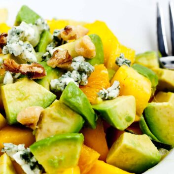 Closeup shot of mango avocado salad with chopped walnuts and blue cheese topping.