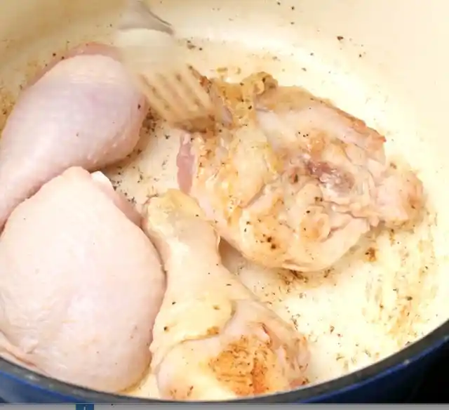 Chicken pieces browning in a pan. 
