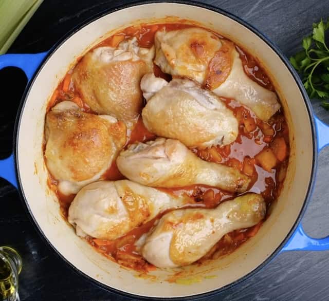 Chicken pieces nestled in a pot with liquids for Moroccan Chicken. 