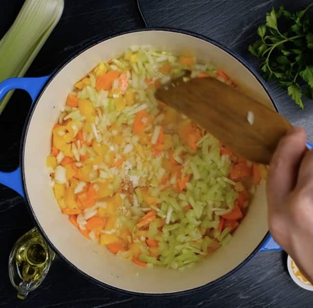 Celery, carrots, onions, and garlic cooking in a pan. 