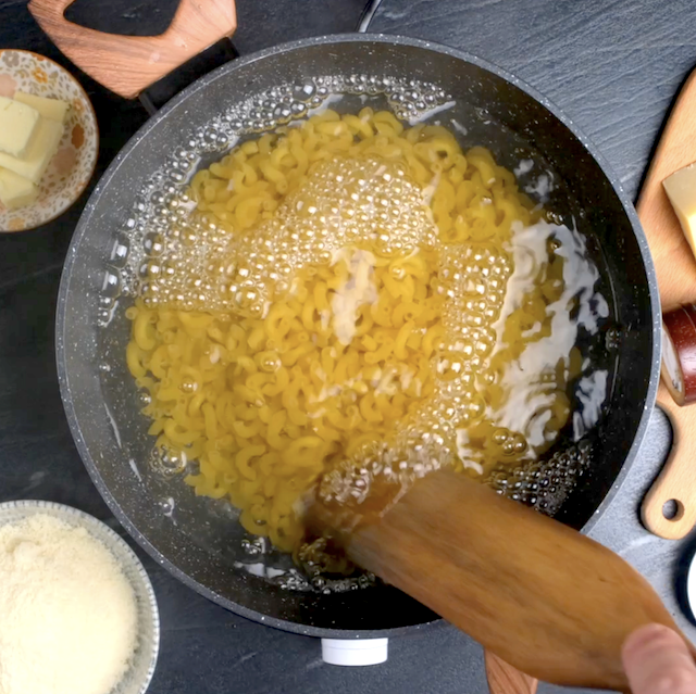 Macaroni being boiled in a pot.