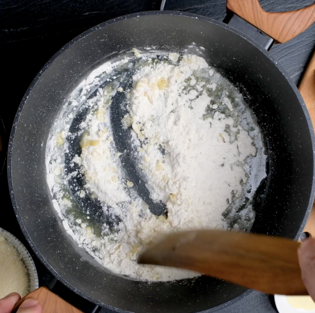 Roux being cooked in a saucepan to make white cheddar mac and cheese.