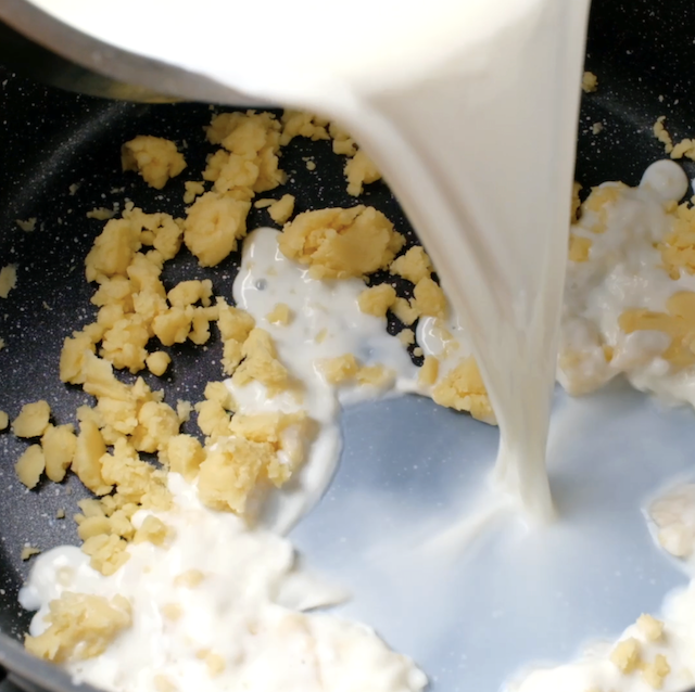 Hot milk being poured into cooked roux mixture.