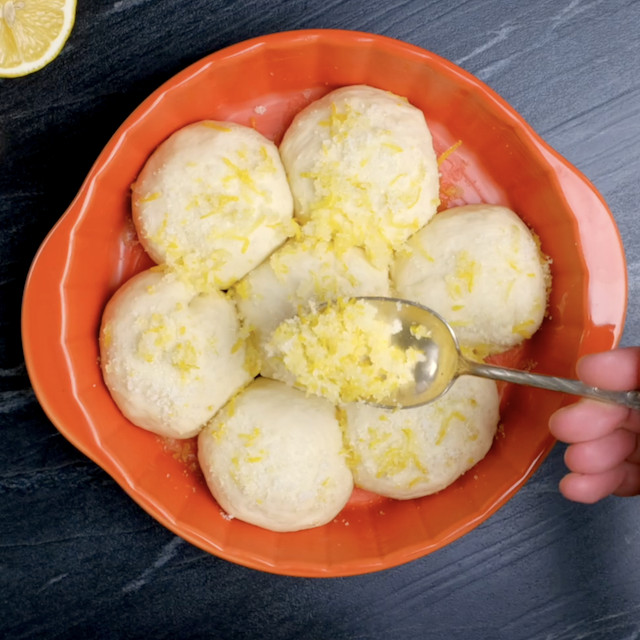 Lemon rolls being sprinkled with lemon-sugar mixture after rising.