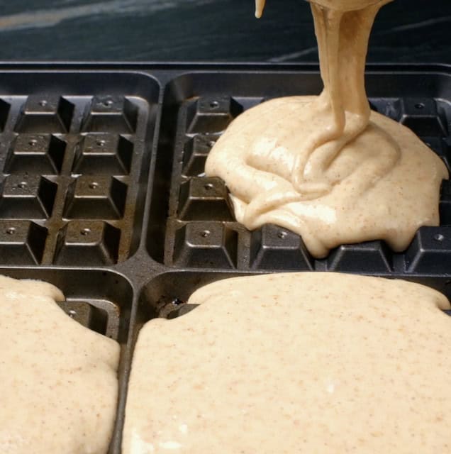 Batter being poured into a greased waffle iron.