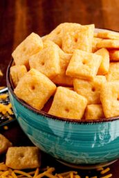 A bowl filled with salted homemade cheese crackers on a wooden surface.