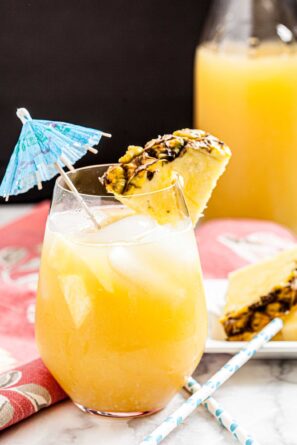 A glass of Hawaiian Mai Tai with ice, garnished with a pineapple slice and a blue umbrella.