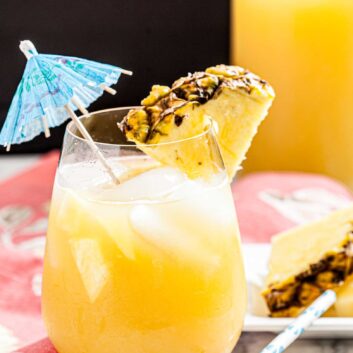 A glass of Hawaiian Mai Tai with ice, garnished with a pineapple slice and a blue umbrella.