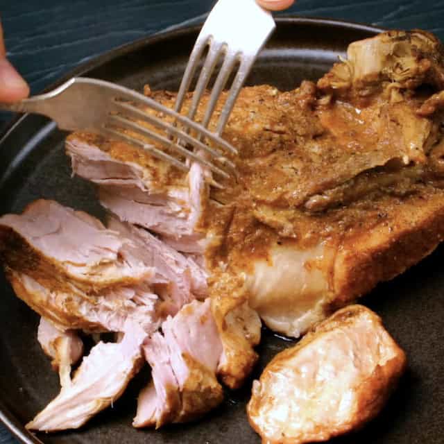 Slow cooked pork being shredded using forks.