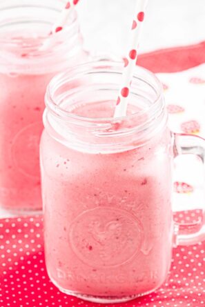 Two mason jars filled with Strawberry Julius with straws.