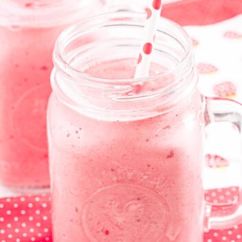 Two mason jars filled with Strawberry Julius with straws.