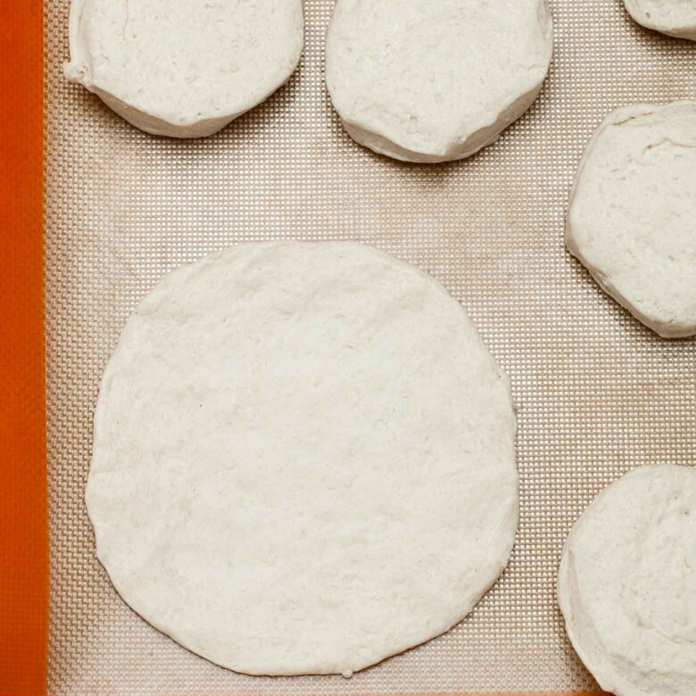 Raw dough rounds placed on a baking mat, ready for baking.