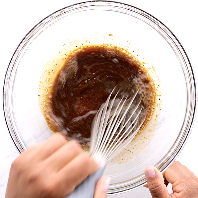 Marinade for pork chops being whisked in a glass bowl.