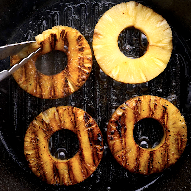 Four pineapple rings being grilled.
