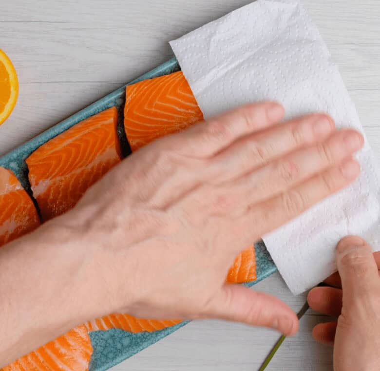 salmon fillets being towel dried before cooking. 