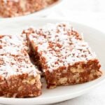Close-up shot of two chocolate peanut butter oatmeal bars, topped with shredded coconut.