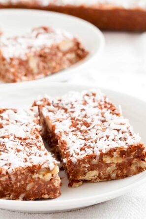 Close-up shot of two chocolate peanut butter oatmeal bars, topped with shredded coconut.