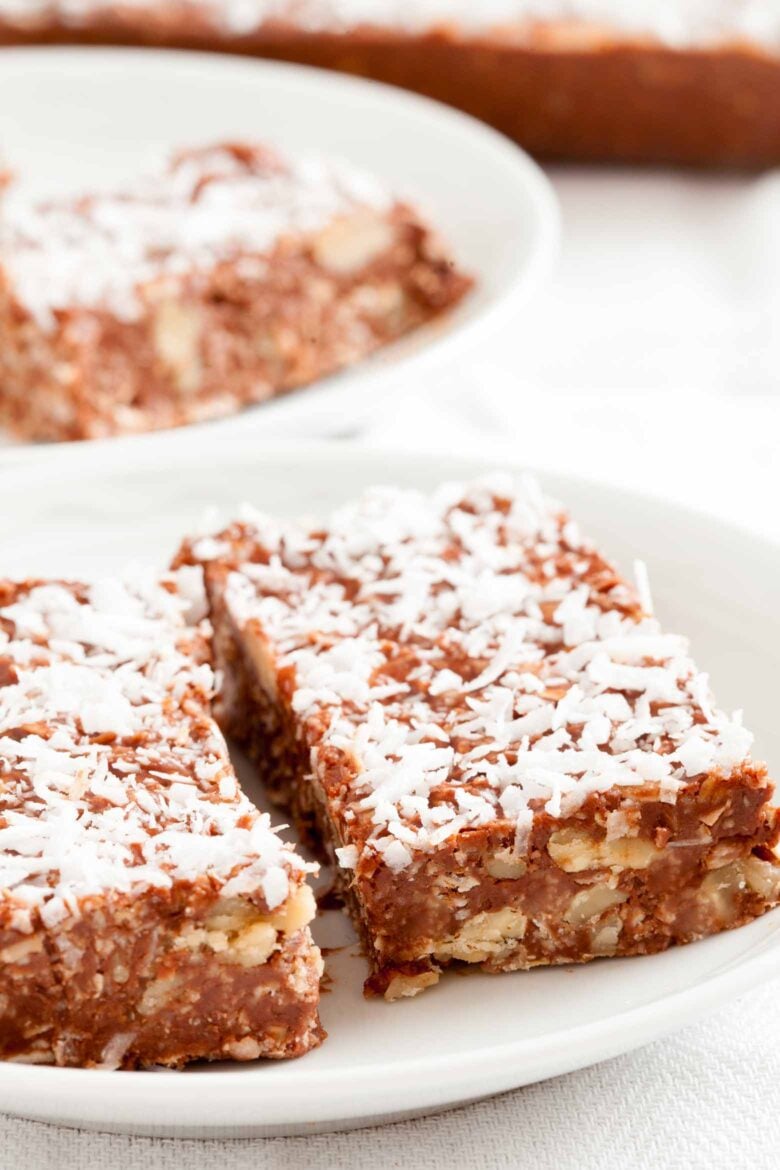Close-up shot of two chocolate peanut butter oatmeal bars, topped with shredded coconut.