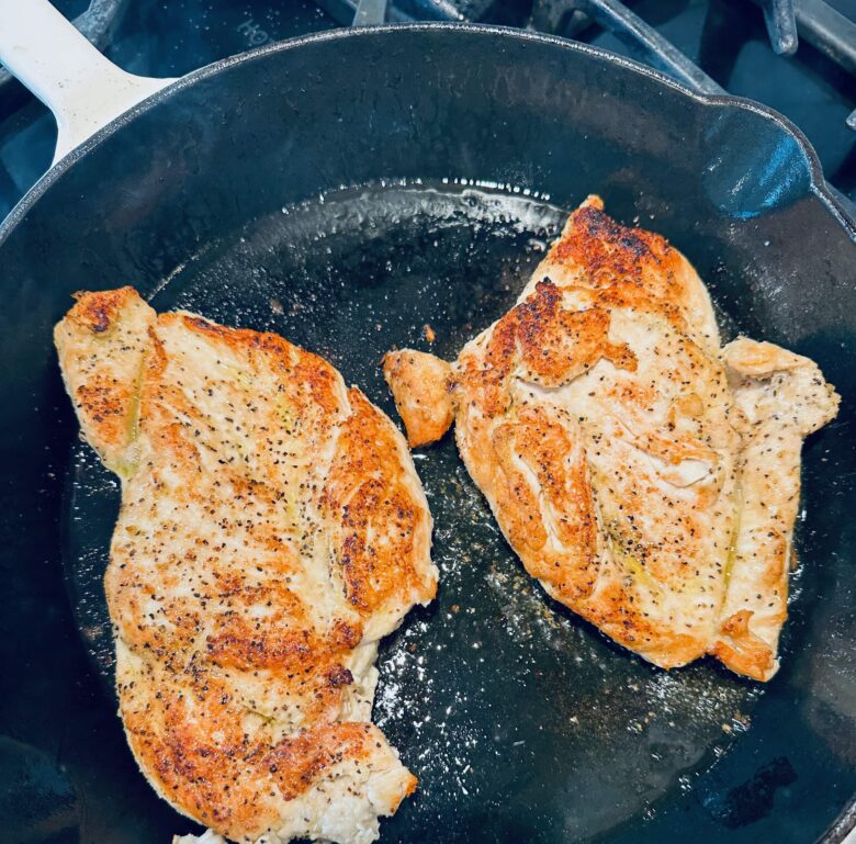 Chicken breast being pan-fried to make healthy chicken Alfredo.