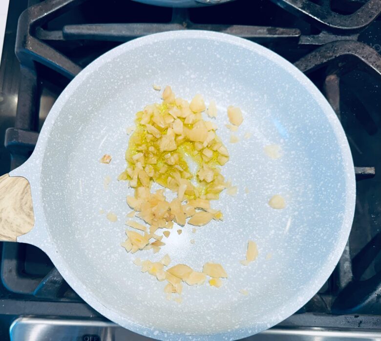 Chopped garlic being sautéed in a pan.