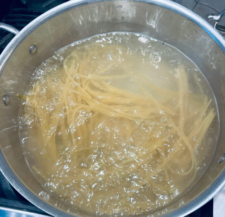 Fettuccini pasta being boiled in a pot of water to make healthy chicken alfredo.