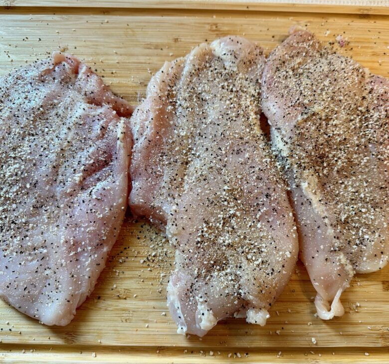 Chicken breast generously seasoned on both sides to make healthy chicken Alfredo at home.