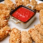 A plate of extra crispy homemade mozzarella sticks served around a delicious dipping sauce.