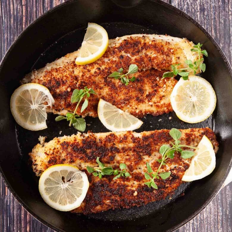 finished pan fried walleye garnished with lemon and herbs.