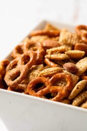 A close-up of a bowl filled with a homemade Gluten Free Chex Mix, including pretzels, almonds, and cereal pieces.