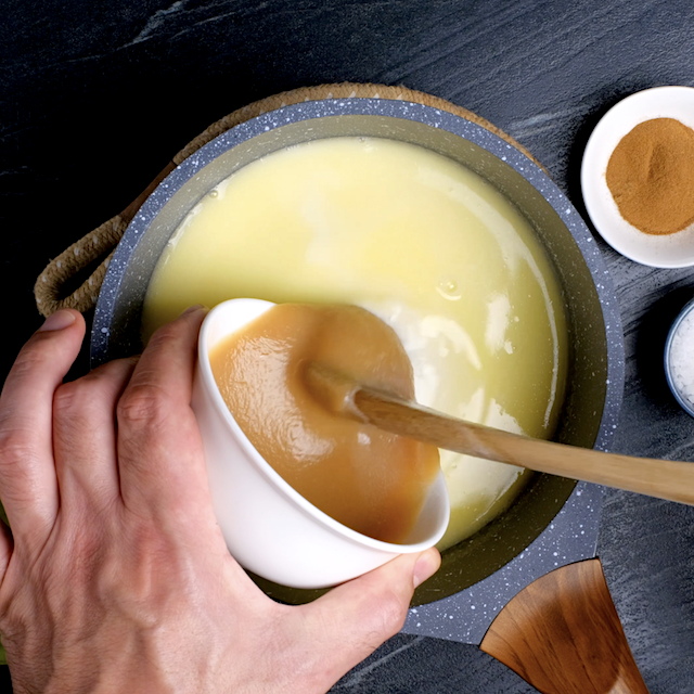 Applesauce being poured into melted butter-sugar mixture to make apple bread pudding.