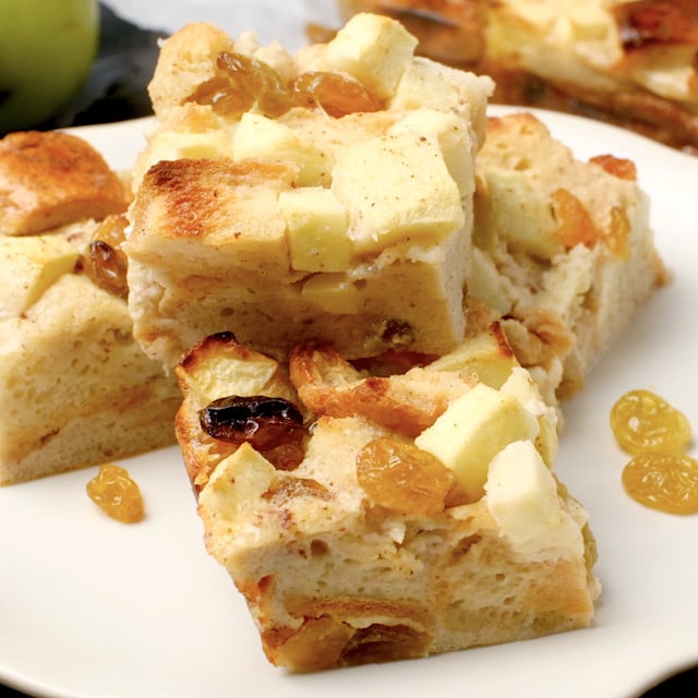 Freshly baked apple bread pudding squares on a white plate.