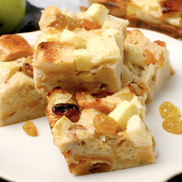 Freshly baked apple bread pudding squares on a white plate.