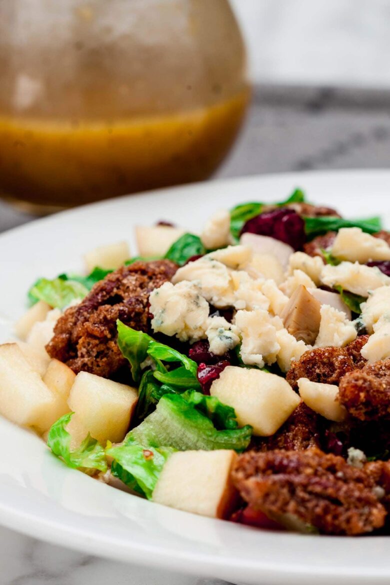 Close-up shot of apple pecan salad, topped with blue cheese and candied pecans.