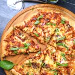 An overhead shot of a freshly baked BBQ chicken pizza on a wooden board.