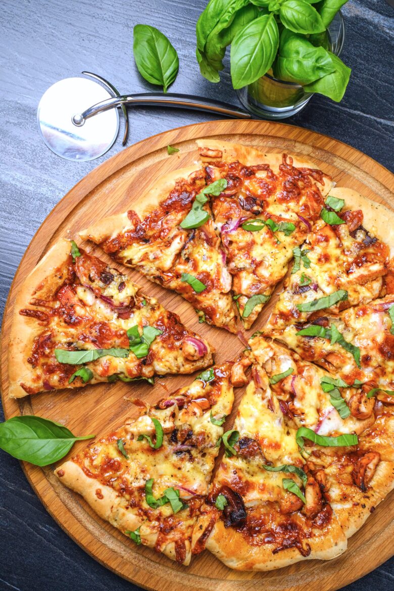 An overhead shot of a freshly baked BBQ chicken pizza on a wooden board.