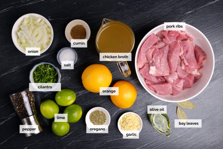 Overhead shot of ingredients to make Cuban mojo pork on a dark surface.