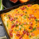 Overhead shot of creamy baked mashed potatoes with cheese and bacon bits on the side.