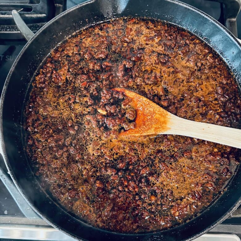 Dan dan noodle sauce ingredients being cooked in a pan.